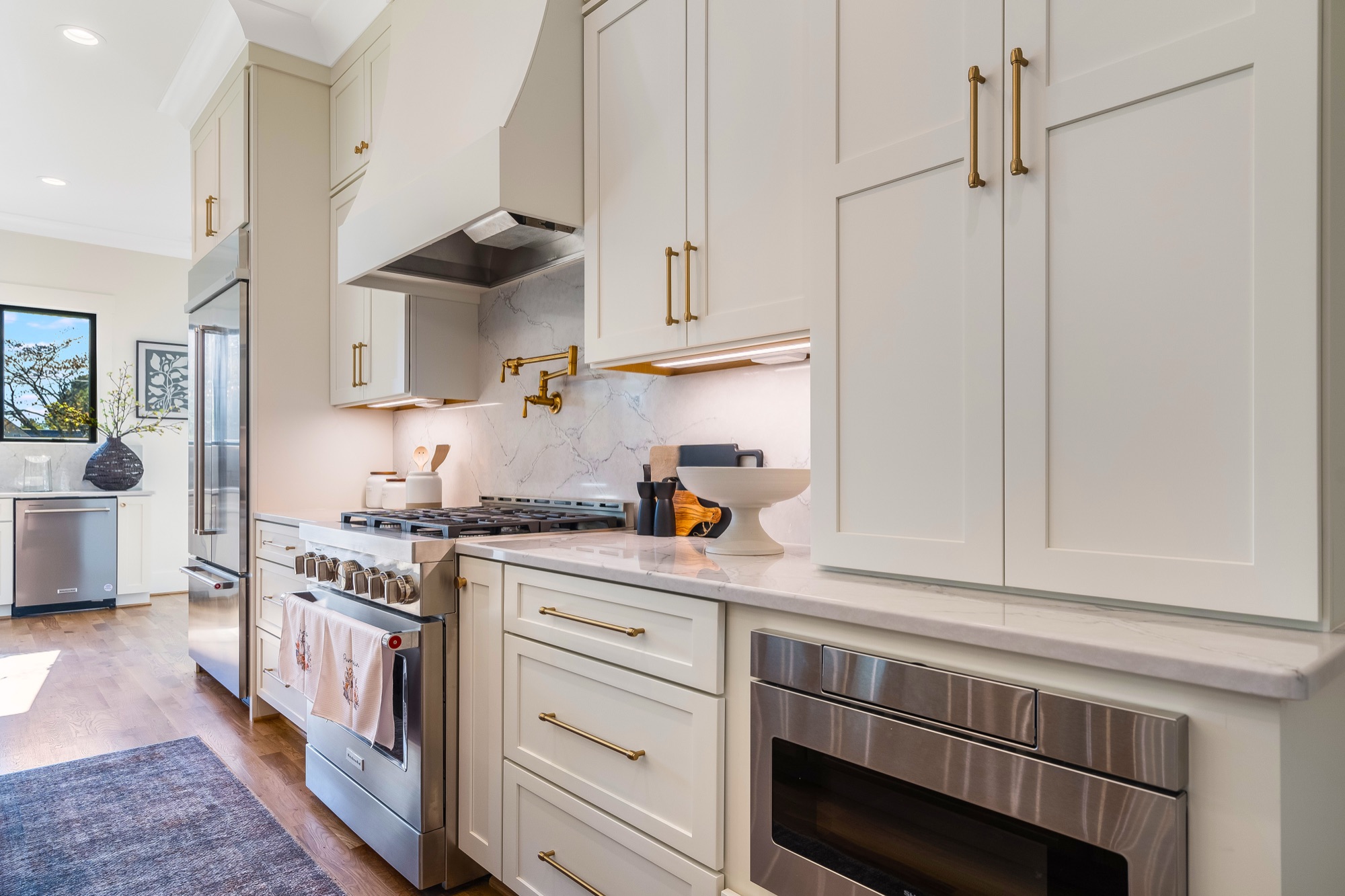 Gemstone gourmet kitchen with custom cabinetry and brass fixtures