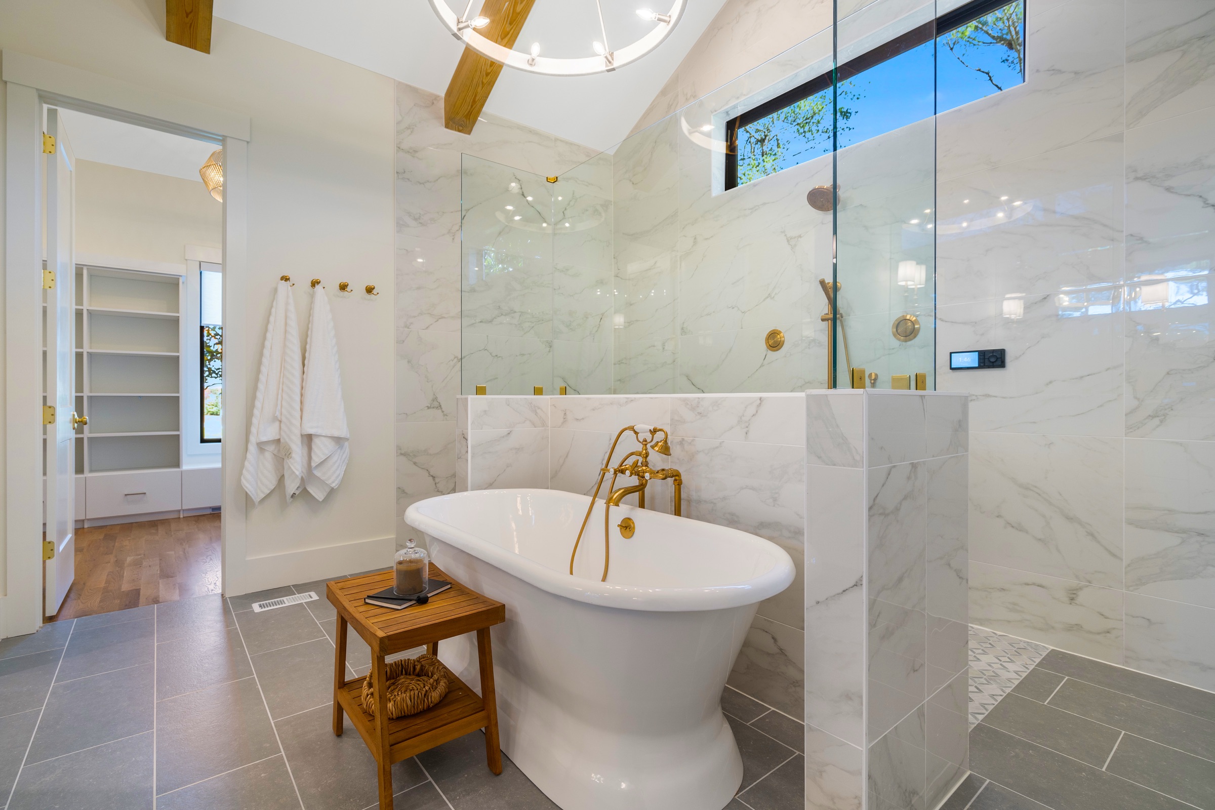 Marble master bath with freestanding tub and brass fixtures