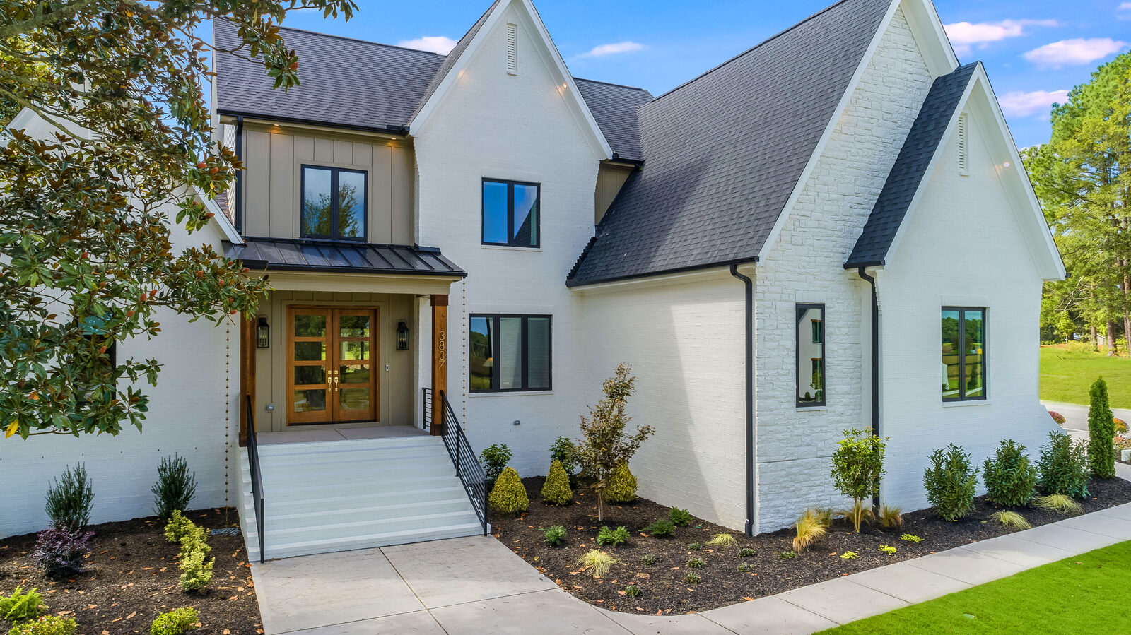 Painted-brick custom home with a covered entry and twin gables by Gemstone Homes